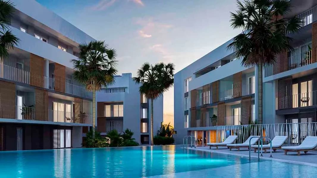 Het buitenzwembad van het UNIC complex bij zonsondergang met palmen